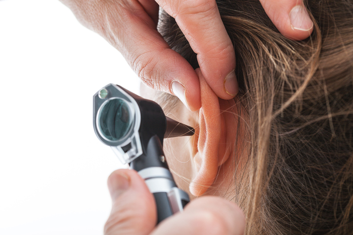 Closeup of examining ear with an otoscope